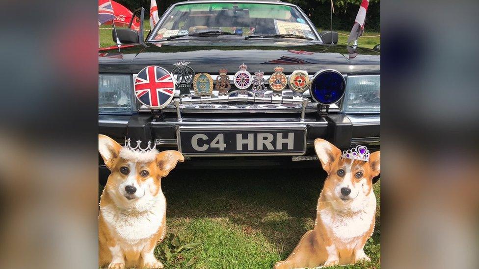 A classic car and two cardboard cut-out corgis