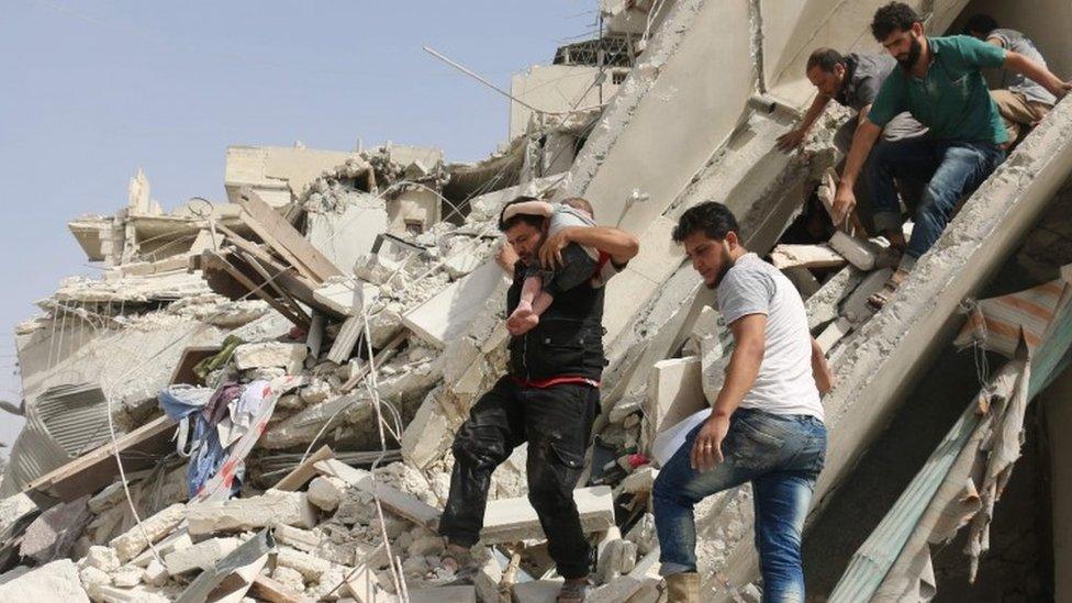 Syrian men remove a baby from the rubble of a destroyed building following a reported air strike in the Qatarji neighbourhood of the northern city of Aleppo (21 September 2016)