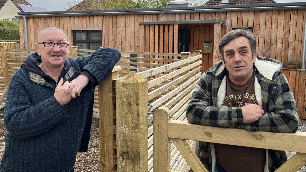 Photo shows Bill Kelly (left) and John Bennett (right), standing in front of John's new home.