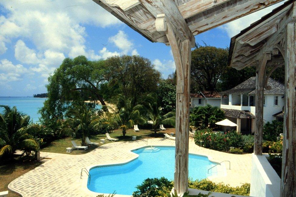 A view of a villa with a pool and the sea in the background