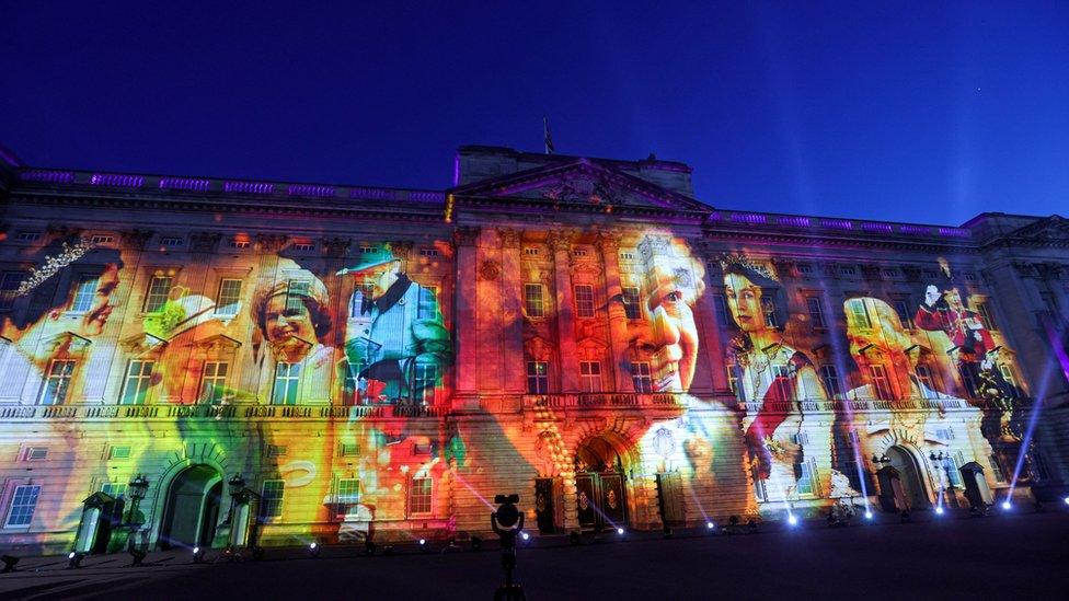 mural of pictures of the queen across buckingham palace