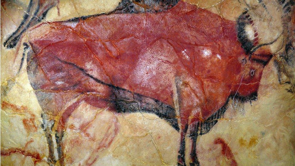 A cave painting of a bright red bison