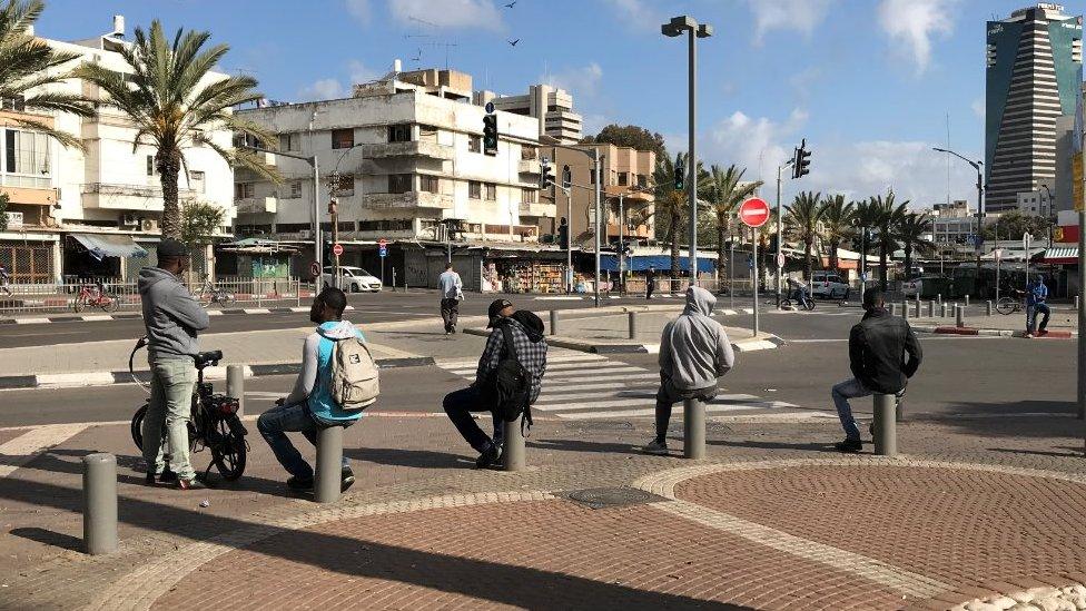 Men sit on bollards in Tel Aviv