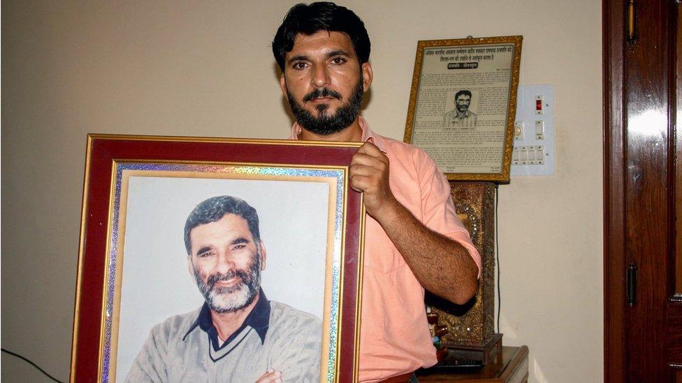 This photo taken on August 25, 2017 shows Indian journalist Anshul Chhatrapati with a portrait of his father Ram Chander Chhatrapati, who controversial religious leader Ram Rahim Singh is accused of killing in 2002, in Sirsa.