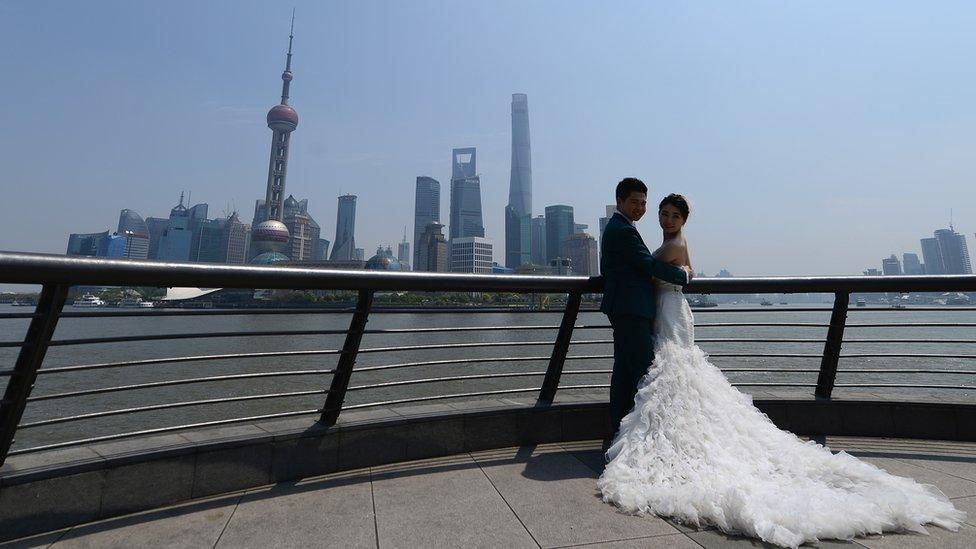 A couple posing for wedding photos with the Shanghai skyline in the background