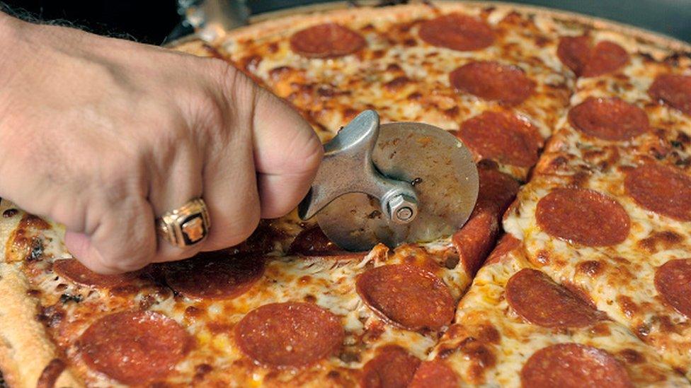 A pepperoni pizza being sliced