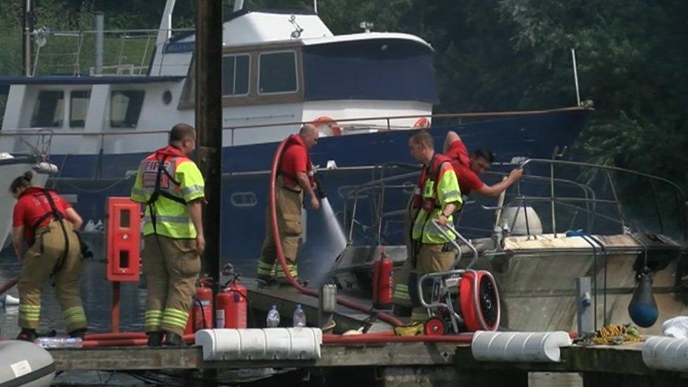 Firefighters with the burnt boat