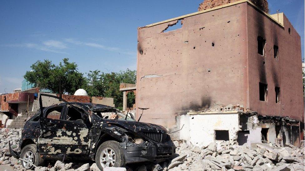 Badly damaged car and building in Cizre, Turkey - May 2016