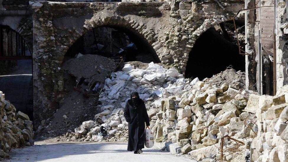 A woman walks past debris in the Syrian city of Aleppo (12 February 2019)