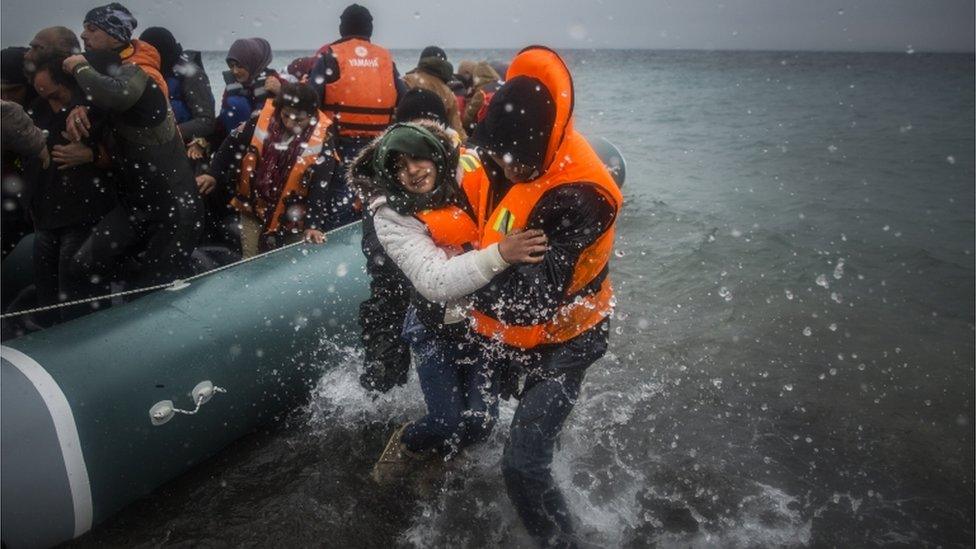 refugees are helped ashore from a dinghy