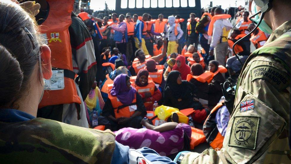 Personnel from HMS Bulwark watch over rescued migrants on board a Royal Navy Landing Craft. May 2015