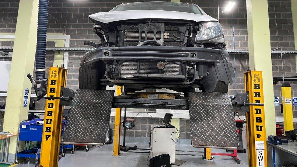 Car with bonnet open raised up on inspection ramp