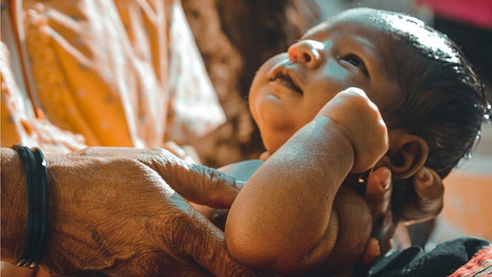 An Indian grandmother holds a newborn boy