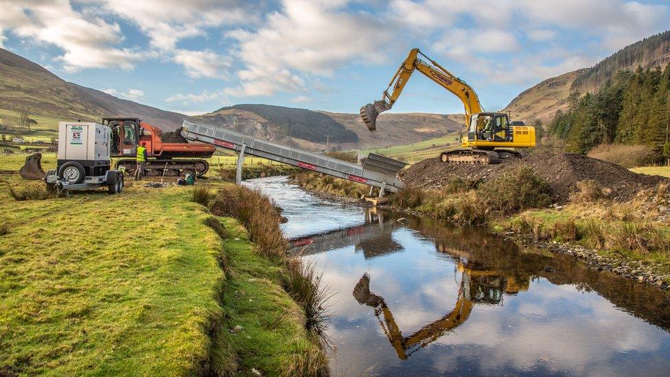 A crane removes the shingle bank on one side of the river