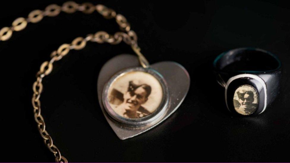 A heart-shaped locket with a photo of a man inside