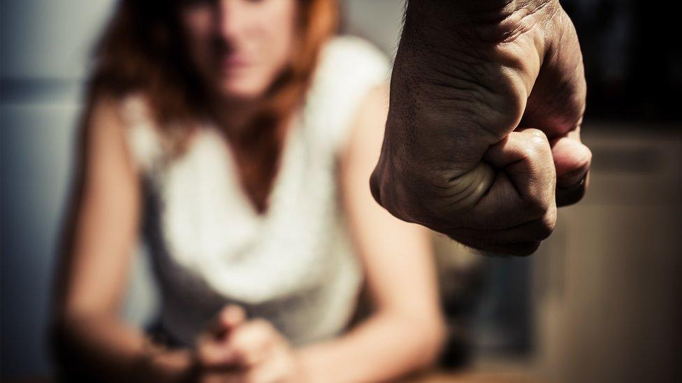 Man with clenched fist standing in front of woman (posed photo)