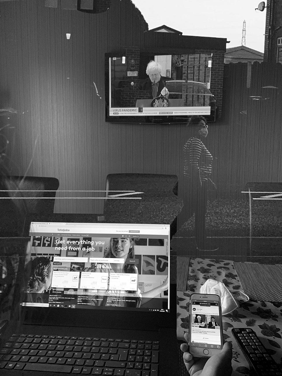 A black-and-white montage of a laptop, phone, television and woman walking past wearing a face mask