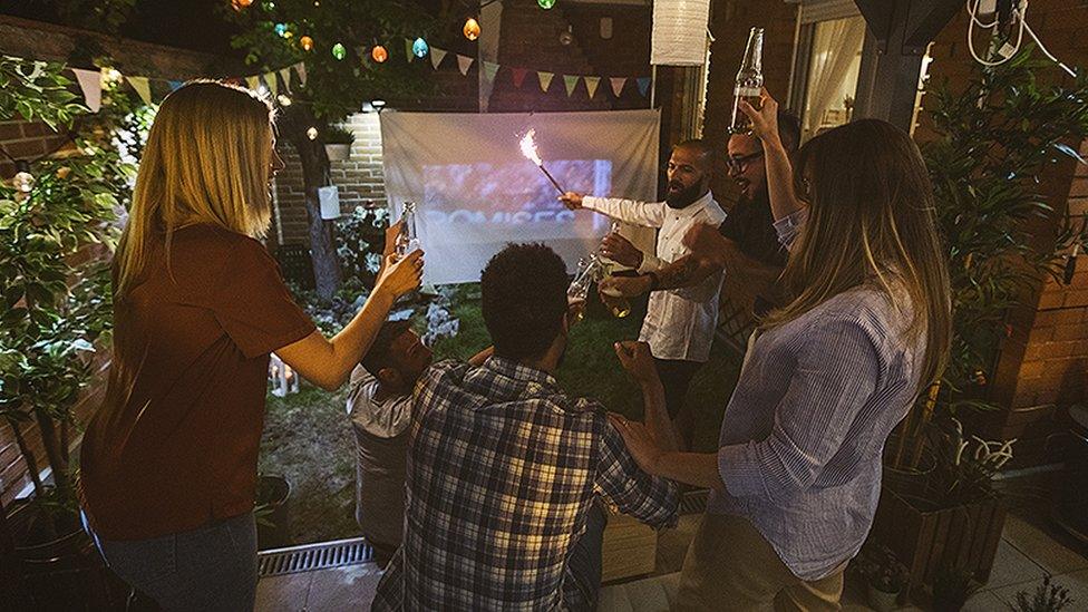 Football fans watching football on a projector screen in a garden