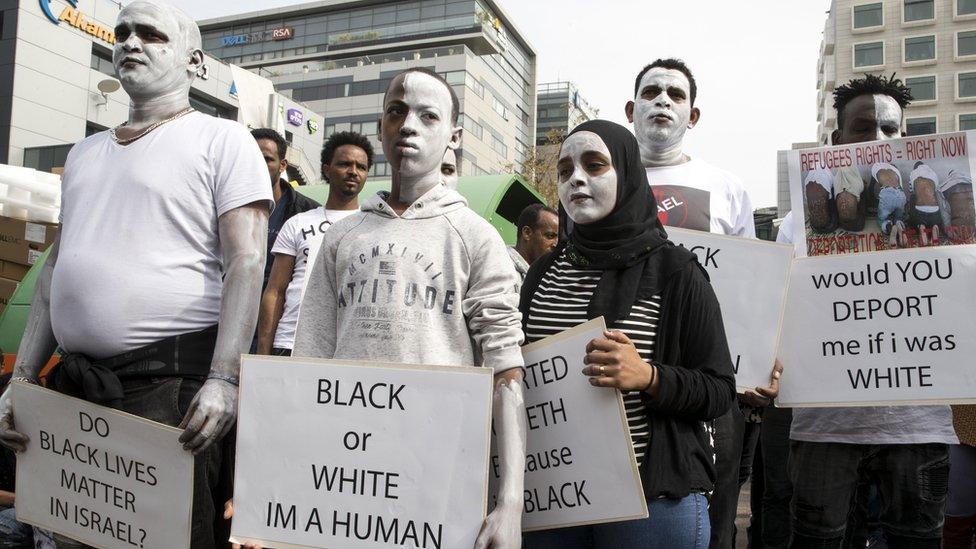 African migrants demonstrate with white paint on their faces, outside the Embassy of Rwanda in the Israeli city of Herzliya on February 7, 2018, against the Israeli government's policy to forcibly deport African refugees and asylum seekers to Rwanda and Uganda.