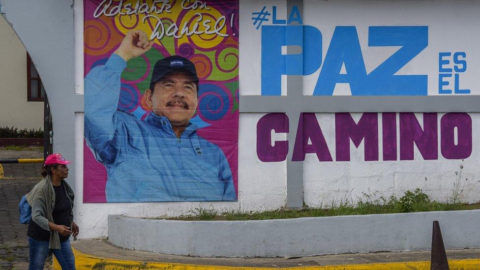 A woman walks in front of a billboard with a picture of Nicaraguan President Daniel Ortega