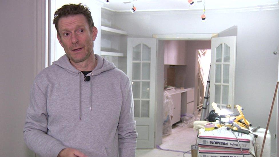 Danny Briottet stands in his living room, which is still being renovated and is surrounded by cement bags, ladders and loose wiring.