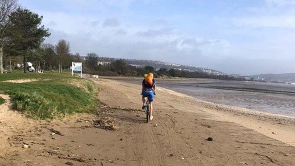 A cyclist rides on the cycle path by Swansea beach