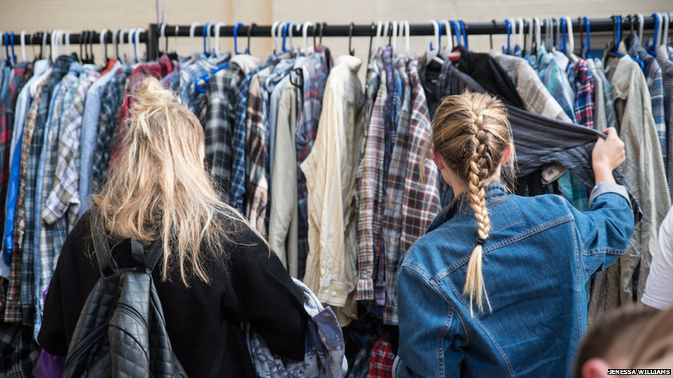 Girls in front of a rack of clothes