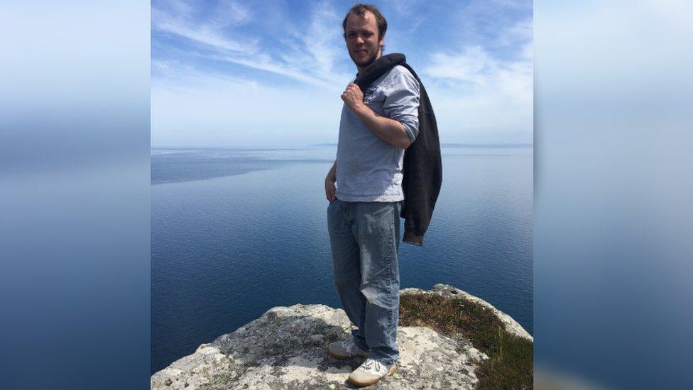 Ben standing on a rock in front of a seascape