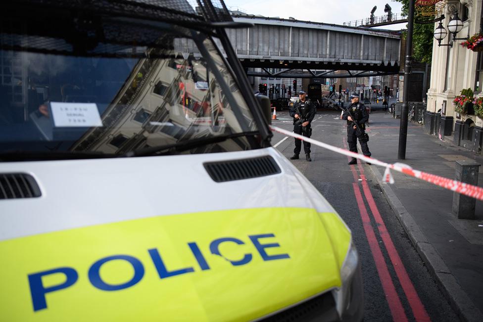 Police van stands next to tape marking the area of Borough Market where Saturday's attacks took place; police officers stand watch behind