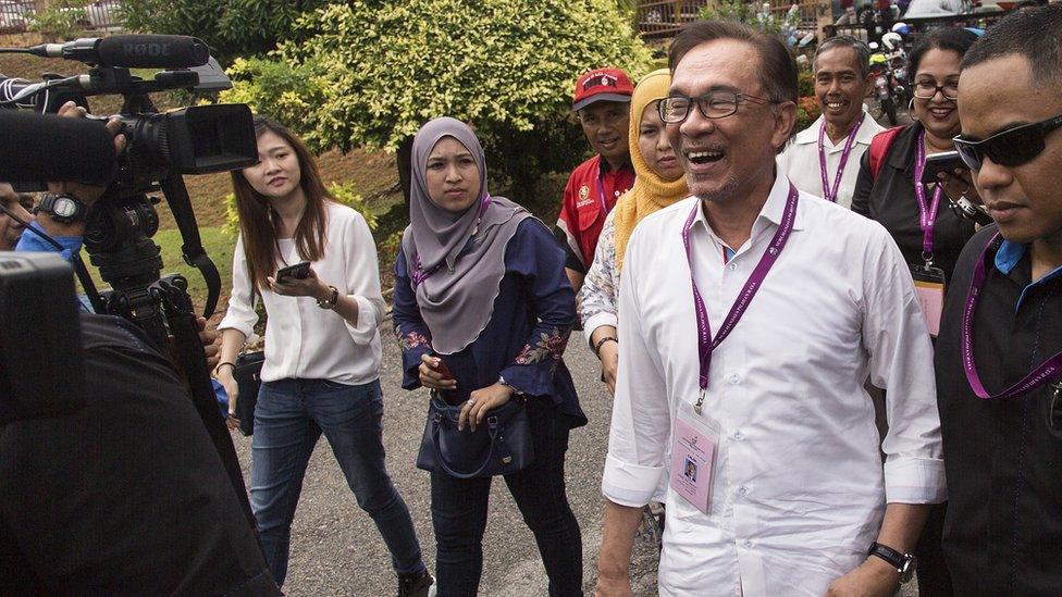 Anwar Ibrahim enjoys a light-hearted moment with member of the media at a polling station