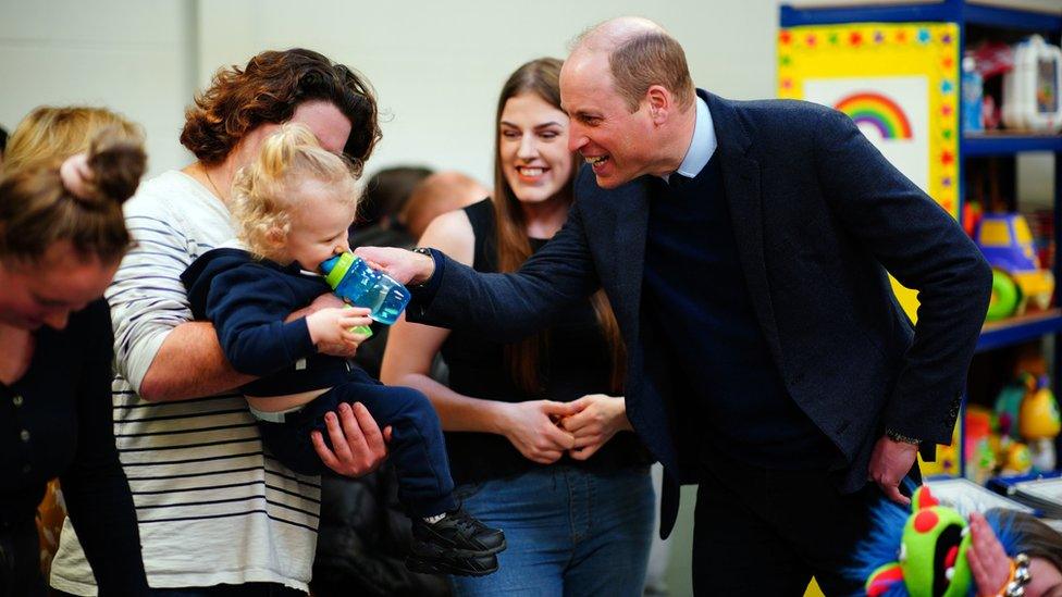 Prince William smiles with a young child