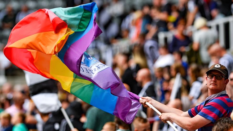 A Newcastle supporter waves a LGBT+ rainbow flag at St James' Park on 30 July 2022 in Newcastle upon Tyne, England