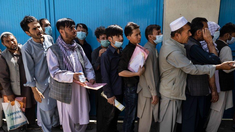 Afghans wait in long lines for hours at the passport office as many are desperate to have their travel documents ready to go on August 14, 2021 in Kabul, Afghanistan.