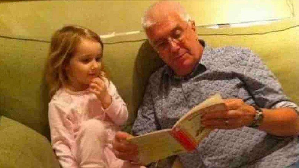 Graham reading to Freya on a sofa as a little girl