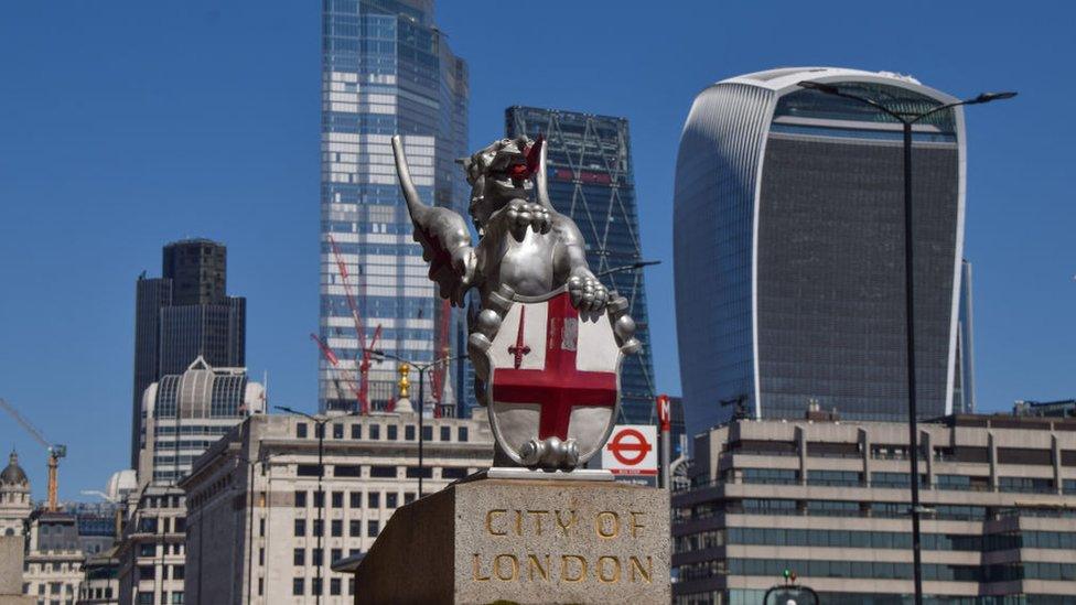 A dragon boundary mark and the City of London skyline on a clear day