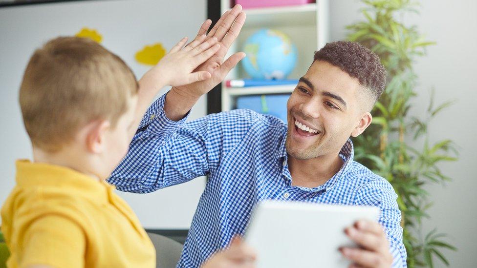 Male teacher high fiving a pupil