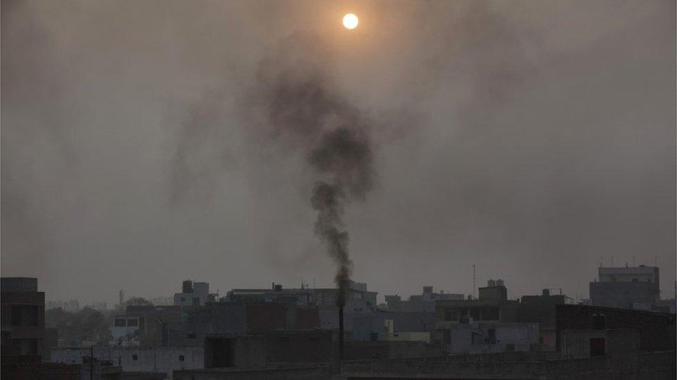 Smoke billows out of a chimney of a small scale factory in New Delhi, India