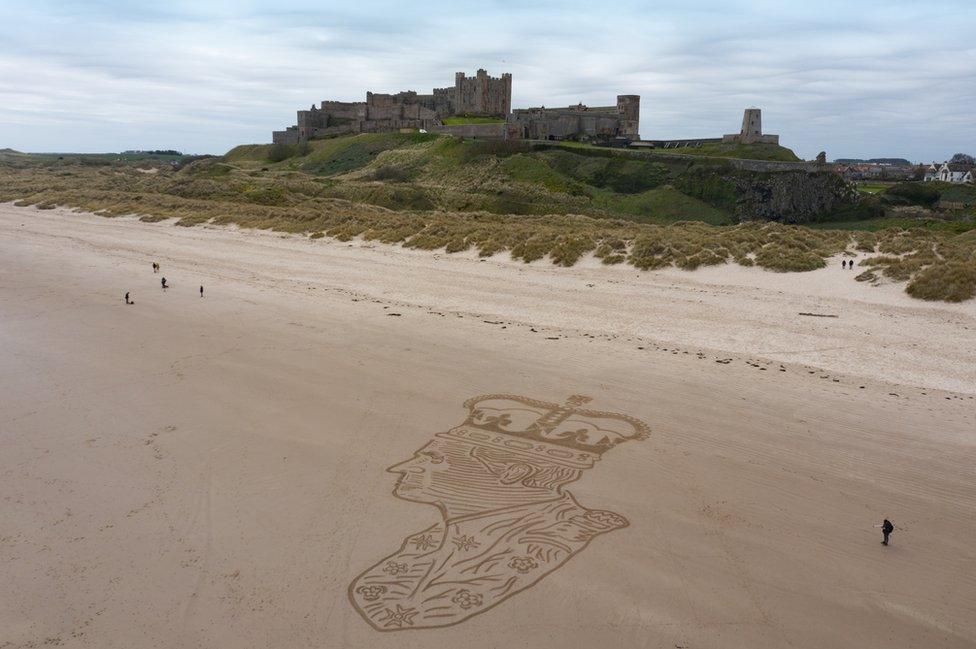 A large picture of King Charles drawn in sand next to a castle