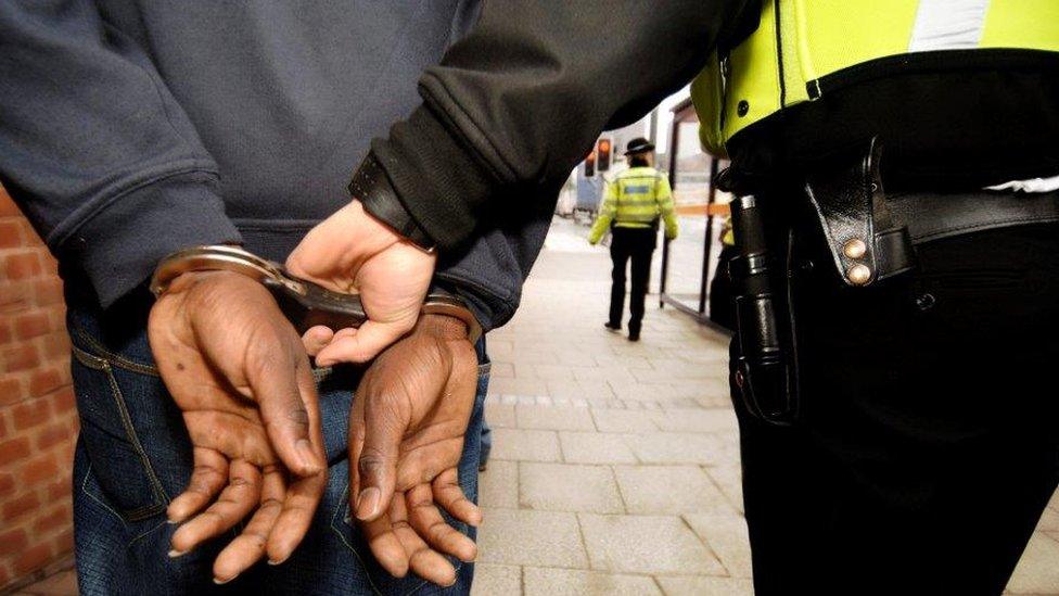 Police officer holds man in handcuffs