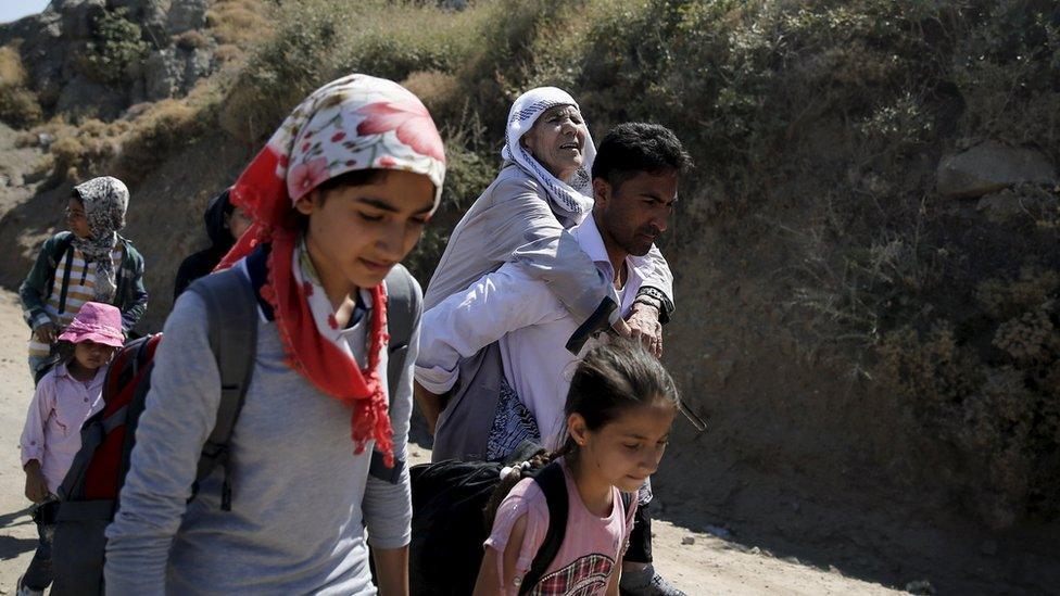 An Afghan migrant carries his grandmother, moments after arriving on a dinghy on the island of Lesbos