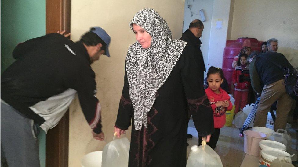 Woman carrying large bottles of water