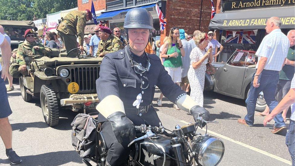 Man dressed in period 1940s policing outfit on a vintage bike