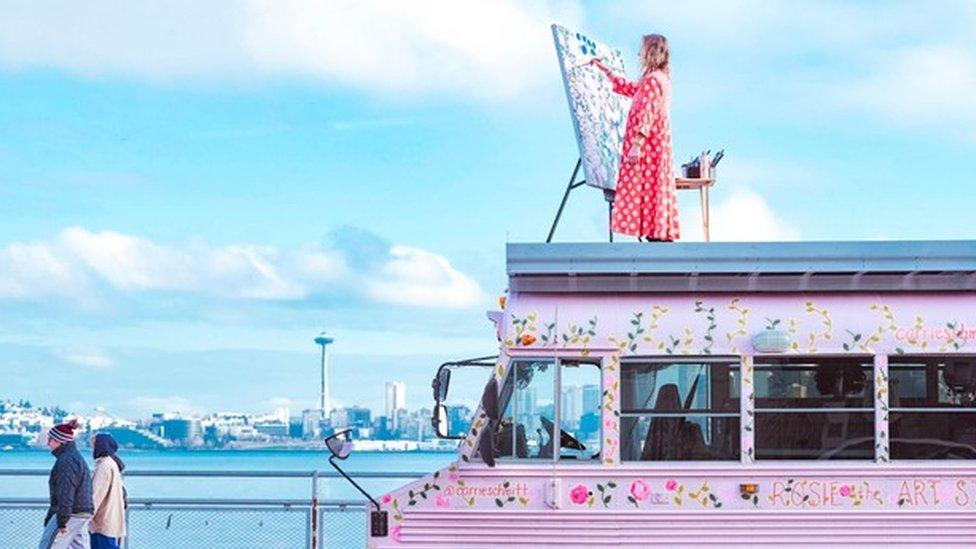 Carrie Schmitt painting on top of her art studio bus, Rosie