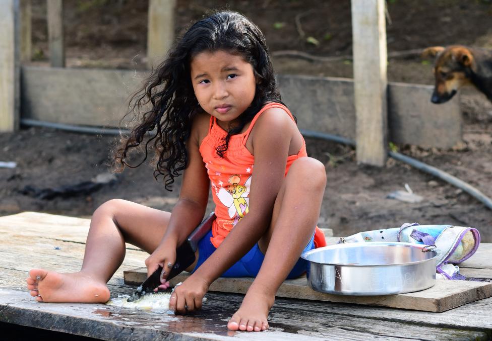 A girl prepares fish at the banks of the river