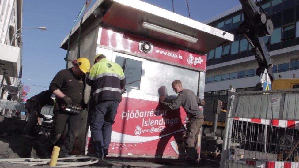 Workmen lift the Baejerins Beztu hot dog stand