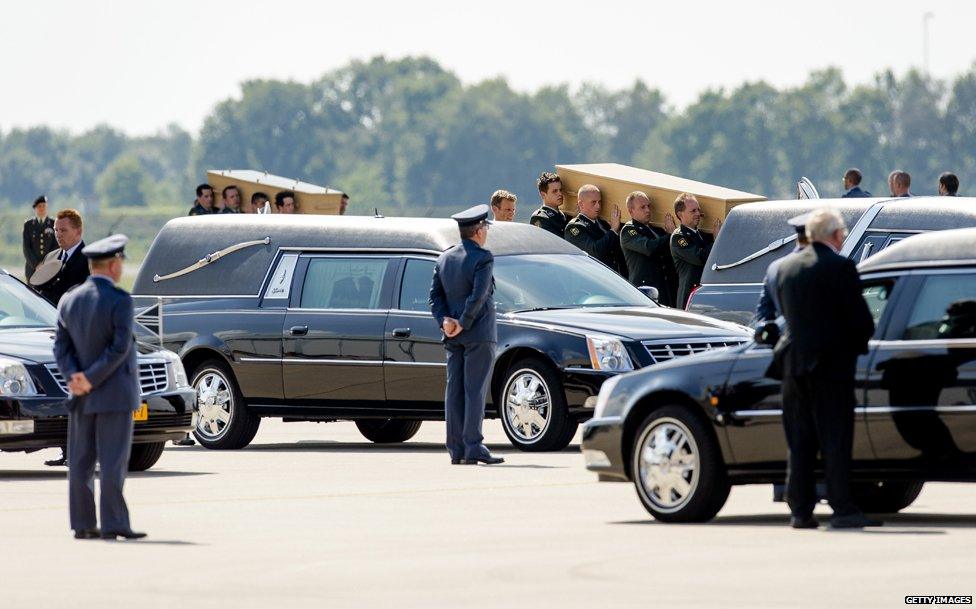 Dutch military personnel carry coffins containing the remains of the victims of the MH17 plane crash to a waiting hearse at the airbase in Eindhoven on July 24, 2014.