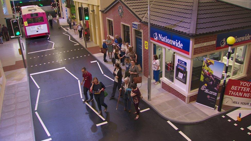 People walk along a street in the mock town used for the dementia event