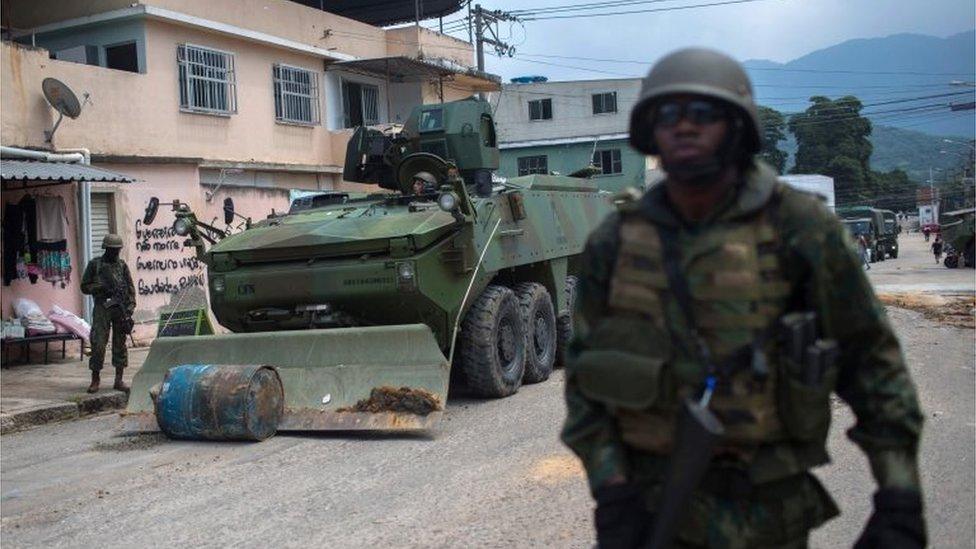 Soldiers of the Armed Forces, backed by armoured vehicles, aircraft and heavy engineering equipment, clear a road blockade as they take part in an operation in the violence-plagued favela of Vila Kennedy, in Rio de Janeiro, Brazil, on March 7, 201