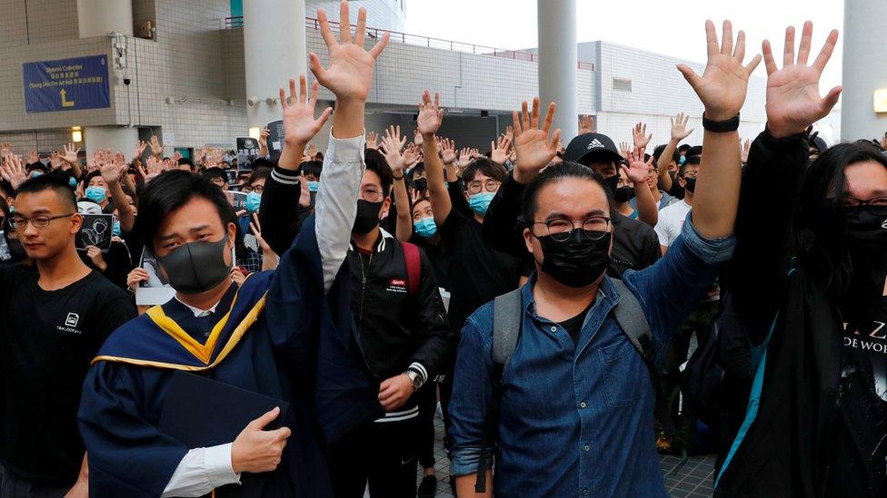 University students hold their hands in the air