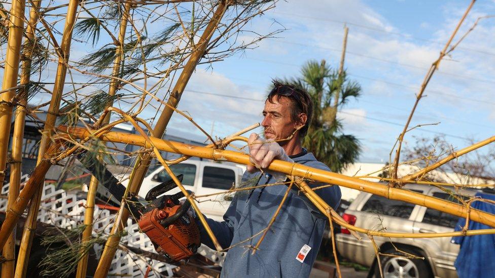 A local resident chainsaws damaged plants from his home in the aftermath of Hurricane Ian in Punta Gorda, Florida, U.S., September 29, 2022